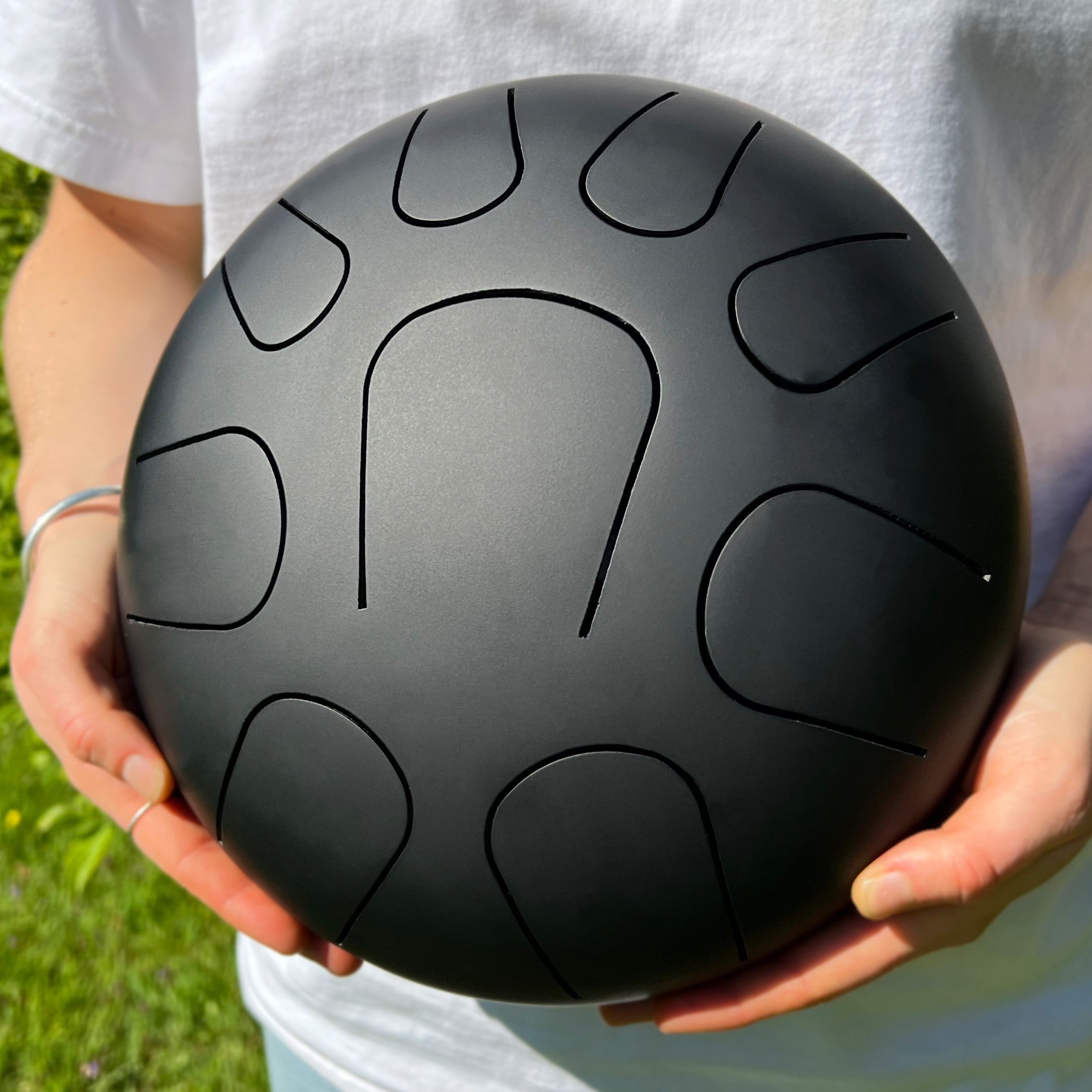 LIDAH® Steel Tongue Drum Zwart vastgehouden in de natuur door muzikant