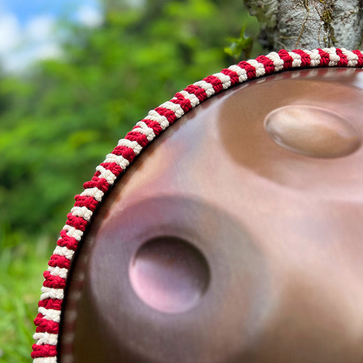 LIDAH Handpan Rope In red Color Aroun a Handpan Against a Tree