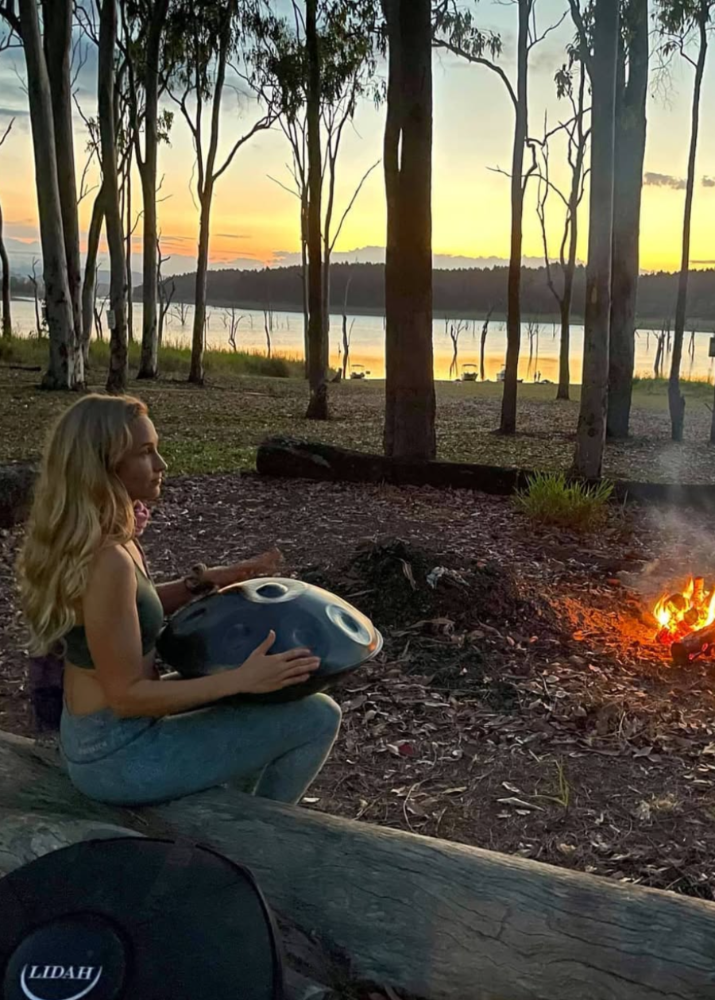Vrouw zit buiten met LIDAH® Handpan op schoot bij zonsondergang