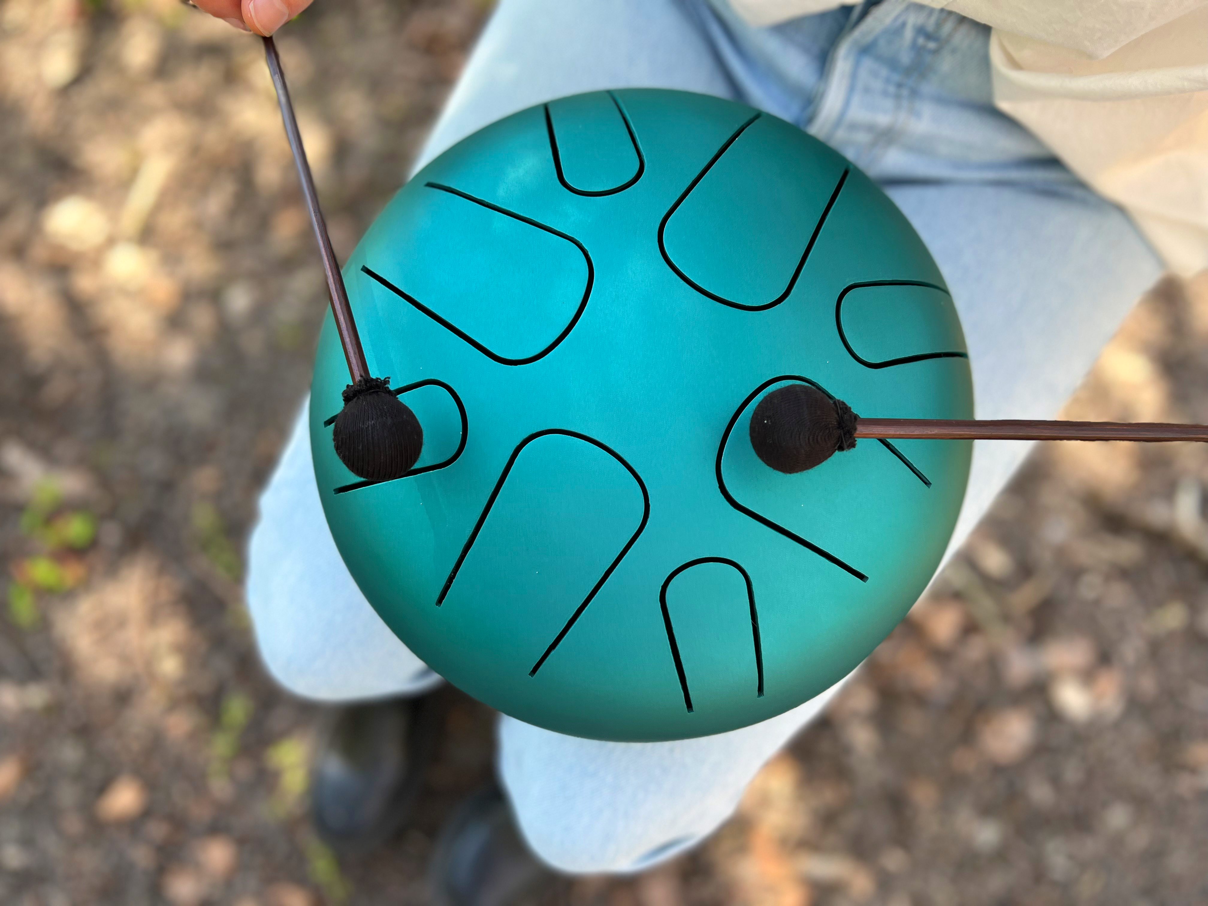 Musician playing LIDAH® Steel Tongue Drum in a peaceful outdoor setting with mallets